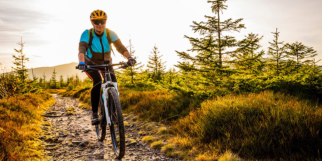 Mountainbiker in hügeliger Landschaft bei Sonnenuntergang