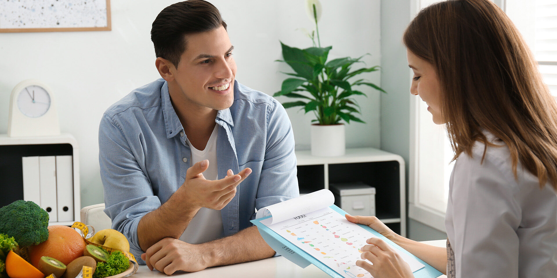 Young nutritionist consulting patient at table in clinic